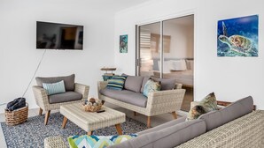 A living room with wicker furniture, a flat-screen TV, and a large window.