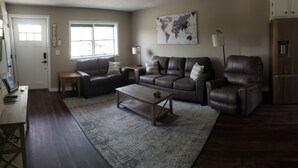 A living room with a sofa set, a coffee table, a rug, a world map on the wall, and a refrigerator. - Freshly updated apartment with ample outdoor space (Burdett)