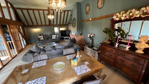 A dining area with a wooden table, grey upholstered seating, and a chandelier. - Couples Retreat Boutique Style Barn Conversion (Great Yarmouth)