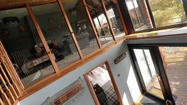 A room with a large window, wooden beams, a sofa, and a mirror. - Couples Retreat Boutique Style Barn Conversion (Great Yarmouth)