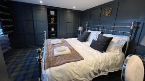 A modern bedroom with a large bed, dark walls, and a decorative headboard. - Couples Retreat Boutique Style Barn Conversion (Great Yarmouth)