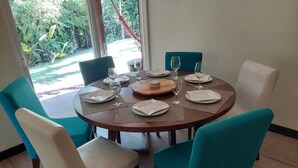 Uma mesa de jantar redonda com quatro cadeiras, um centro de mesa de madeira e vista para o verde lá fora.