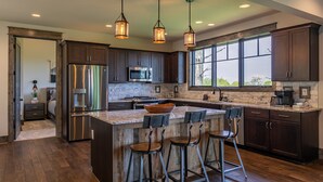 A modern kitchen with dark wood cabinets, stainless steel appliances, and a large island with bar stools.