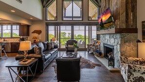 A spacious living area with a fireplace, leather furniture, and large windows offering a view of the outdoors.