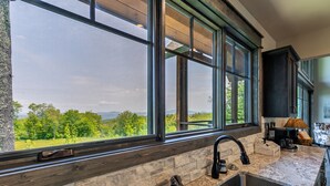 A kitchen with large windows, a granite countertop, and a sink.
