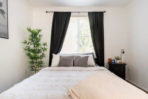 Relax in this serene bedroom with a large bed, bamboo plant, and a cozy reading nook.