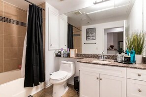 Bathroom features a white toilet, black shower curtain, and granite countertop.