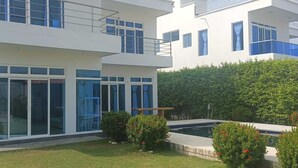 Ein modernes, zweistöckiges Haus mit großen Glasfenstern und einem Swimmingpool im Hinterhof.