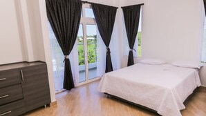 Ein Schlafzimmer mit einem Bett, einem Kleiderschrank und einer Glastür, die auf einen Balkon führt.
