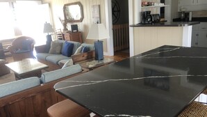 Un accogliente soggiorno con un grande tavolo nero, mobili in legno e un angolo cottura sullo sfondo.
