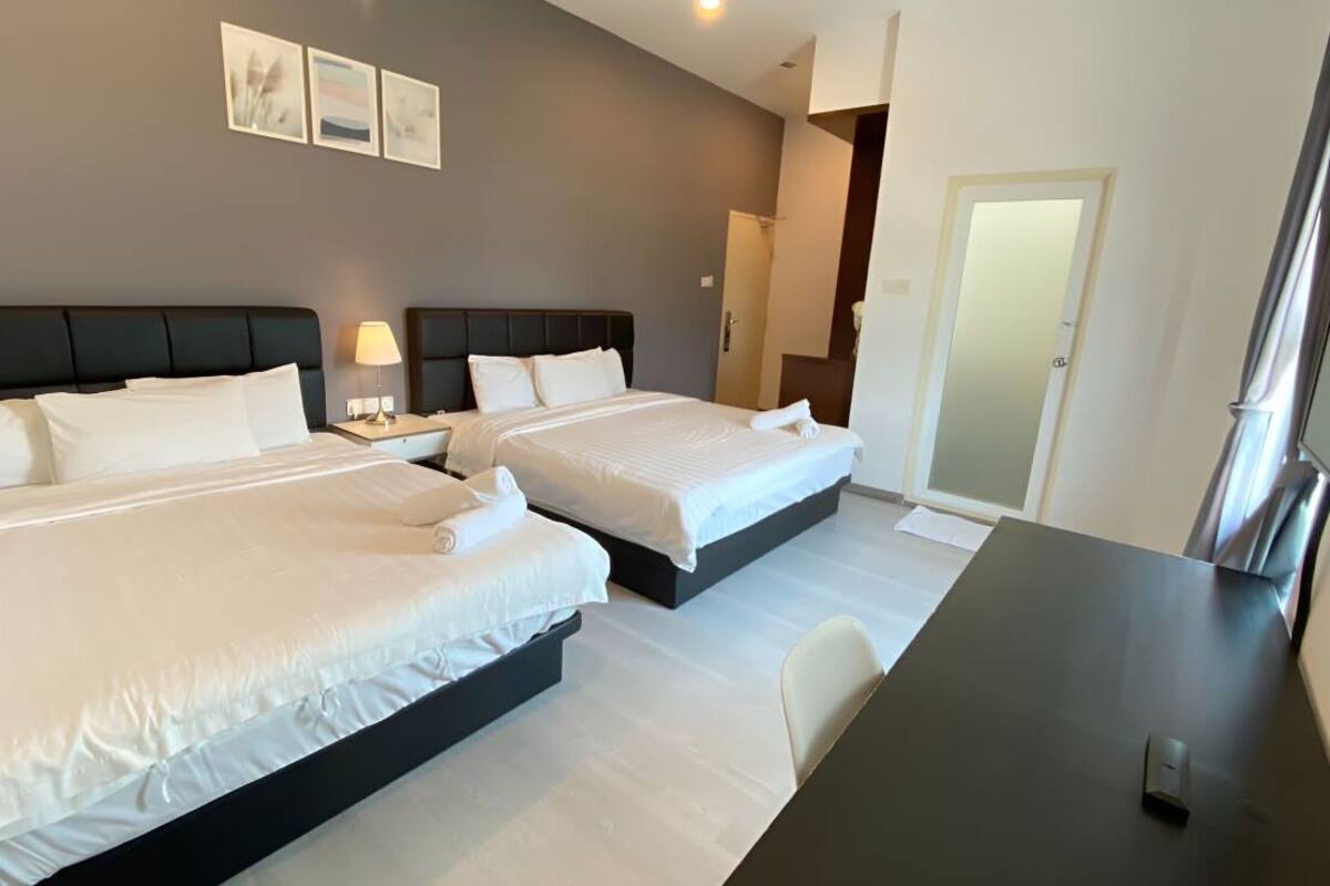 A hotel room with two beds, a desk, and a TV.