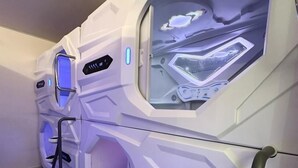 Fileira de cadeiras de massagem futuristas com painéis de controle e apoio para os pés.