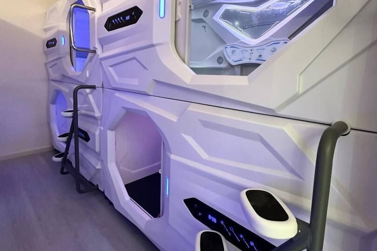A row of futuristic massage chairs with control panels and footrests.