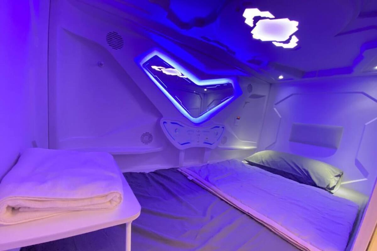 A modern room with a bed, a small table, and a neon heart-shaped light fixture on the wall.