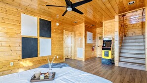 Een houten chalet inrichting met een bed, een plafondventilator, een open haard en een kleine kitchenette.