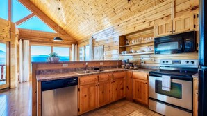 Een houten keuken in een chalet, met een vaatwasser, fornuis en magnetron.