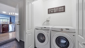 A laundry room with two white front-loading washing machines and a wall-mounted dryer.