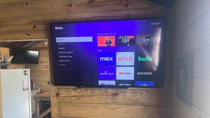 Un téléviseur Roku fixé à un mur en bois, affichant l’interface Roku avec différentes options de menu et icônes d’applications.