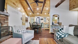 A cozy living room with a fireplace, a dining area, and a kitchen.