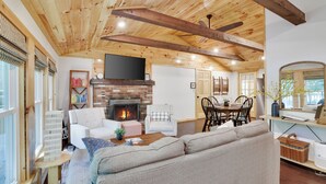 A cozy living room with a fireplace, a sofa, and a dining area with chairs and a table.