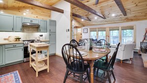 A spacious kitchen with light blue cabinets, a wooden dining table with chairs, and a ceiling fan.