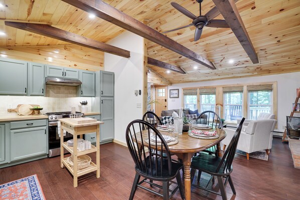 A spacious kitchen with light blue cabinets, a wooden dining table with chairs, and a ceiling fan.