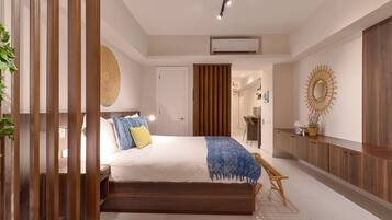 A modern bedroom with a large bed, wooden headboard, and a bedside table.