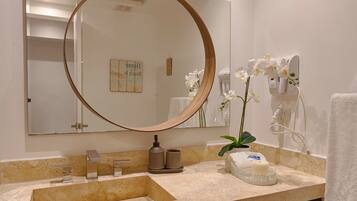 Un bagno con uno specchio grande, un lavandino, un portascopevoli e un asciugacapelli.