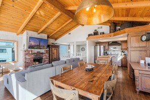 Ein geräumiges Wohnzimmer mit einem großen Esstisch aus Holz, einem Kamin und einer gemütlichen Sitzecke.