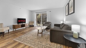 Un salon moderne avec un téléviseur à écran plat, un canapé, une table basse et une lampe.