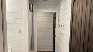 A narrow hallway with white wooden walls and a brown floor. There is a door on the right and a bench on the left. - 4 Bedroom 3 Bath Lakefront Home with Private Dock, Secluded, Lewis Smith Lake (Double Springs)