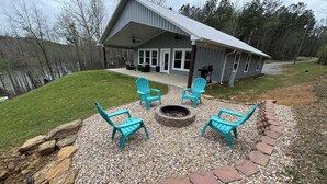 A house with a covered patio area featuring a fire pit and four turquoise Adirondack chairs. - 4 Bedroom 3 Bath Lakefront Home with Private Dock, Secluded, Lewis Smith Lake (Double Springs)