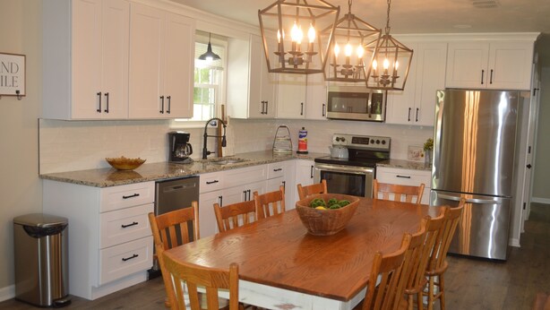 A modern kitchen with white cabinetry, a wooden dining table, and a stainless steel refrigerator. - Gainesboro, TN House, Dale Hollow Lake, Standing Stone State Park, Roaring River (Gainesboro)