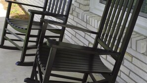 Three wooden rocking chairs positioned on a concrete porch in front of a house with white brick siding and dark shutters. - Gainesboro, TN House, Dale Hollow Lake, Standing Stone State Park, Roaring River (Gainesboro)