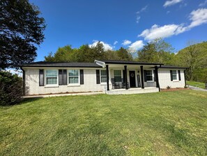 A single-story house with a porch, a welcome sign, and a well-maintained lawn.