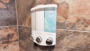A wall-mounted shower with a transparent water tank, a shampoo dispenser, and a body wash dispenser. - Cozy & Clean 4BR/2BA in South Tyler (Tyler)