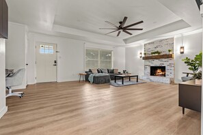 A spacious living room with a fireplace, a ceiling fan, and a seating area with a sofa and coffee table.