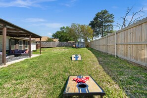 A backyard with a wooden deck, a covered seating area, and a wooden fence. - Cozy & Clean 4BR/2BA in South Tyler (Tyler)