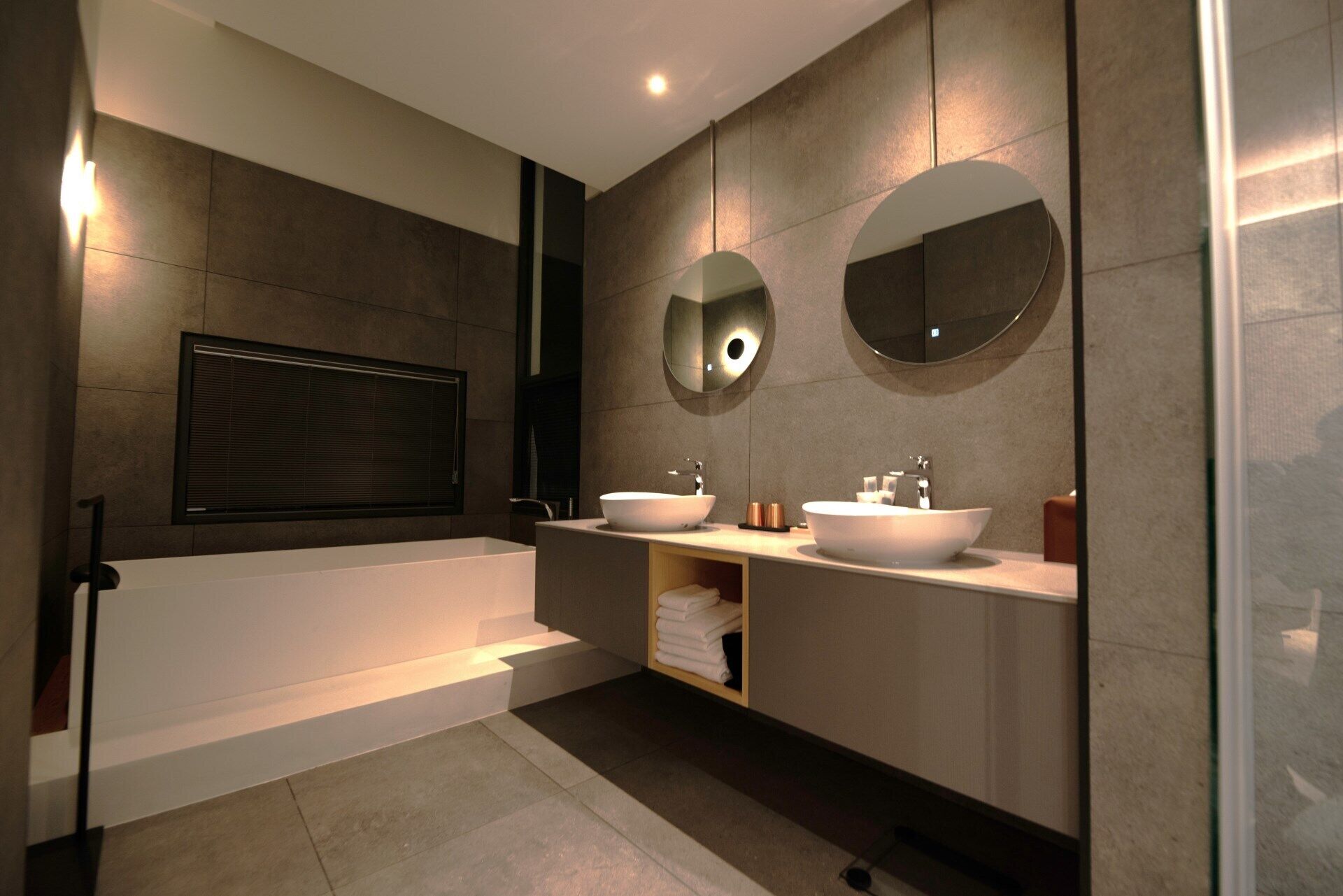 A modern bathroom with a bathtub, two sinks, and large mirrors.