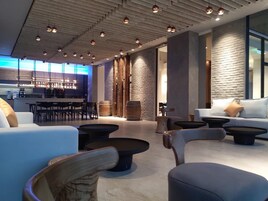 Un área de lounge moderna con bar, asientos y una pared de piedra.