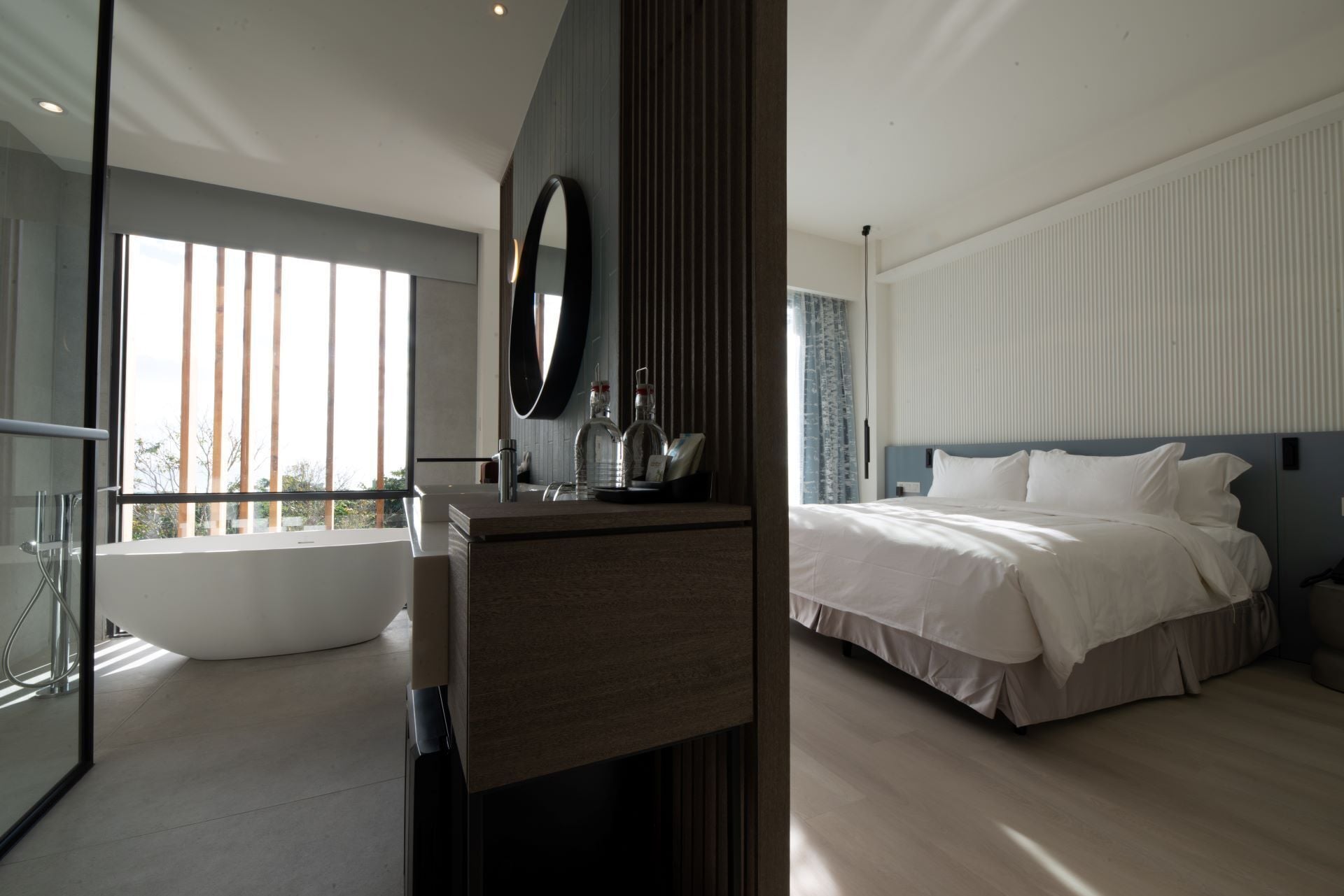 Een moderne hotelkamer met een groot bed, een badkamer met bad en een balkon met uitzicht.