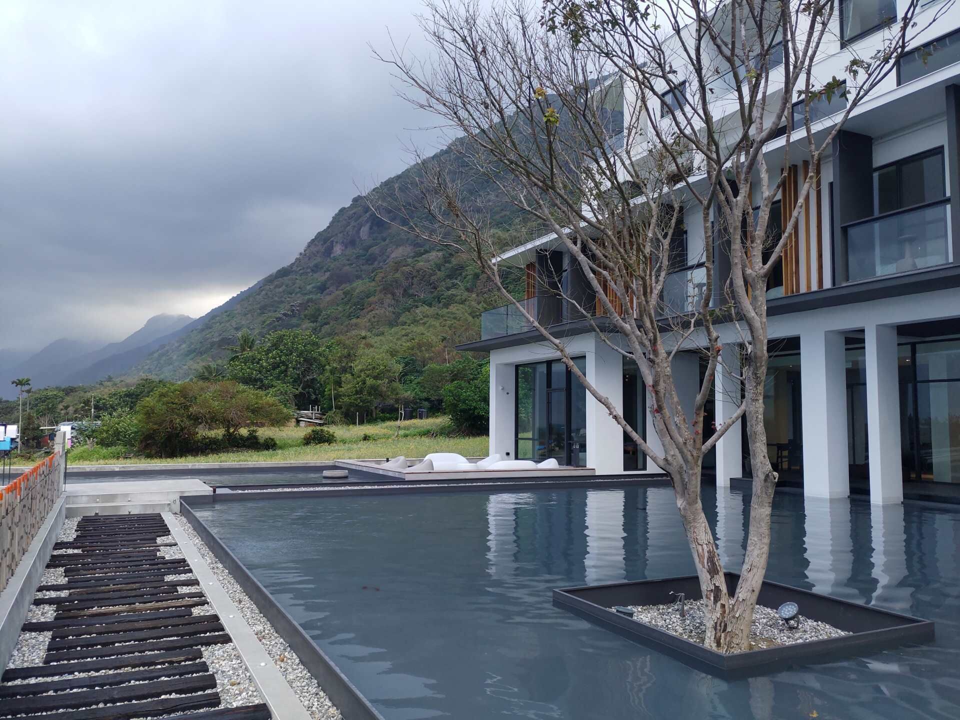Un bâtiment moderne doté d’un espace piscine, entouré de montagnes et de verdure.