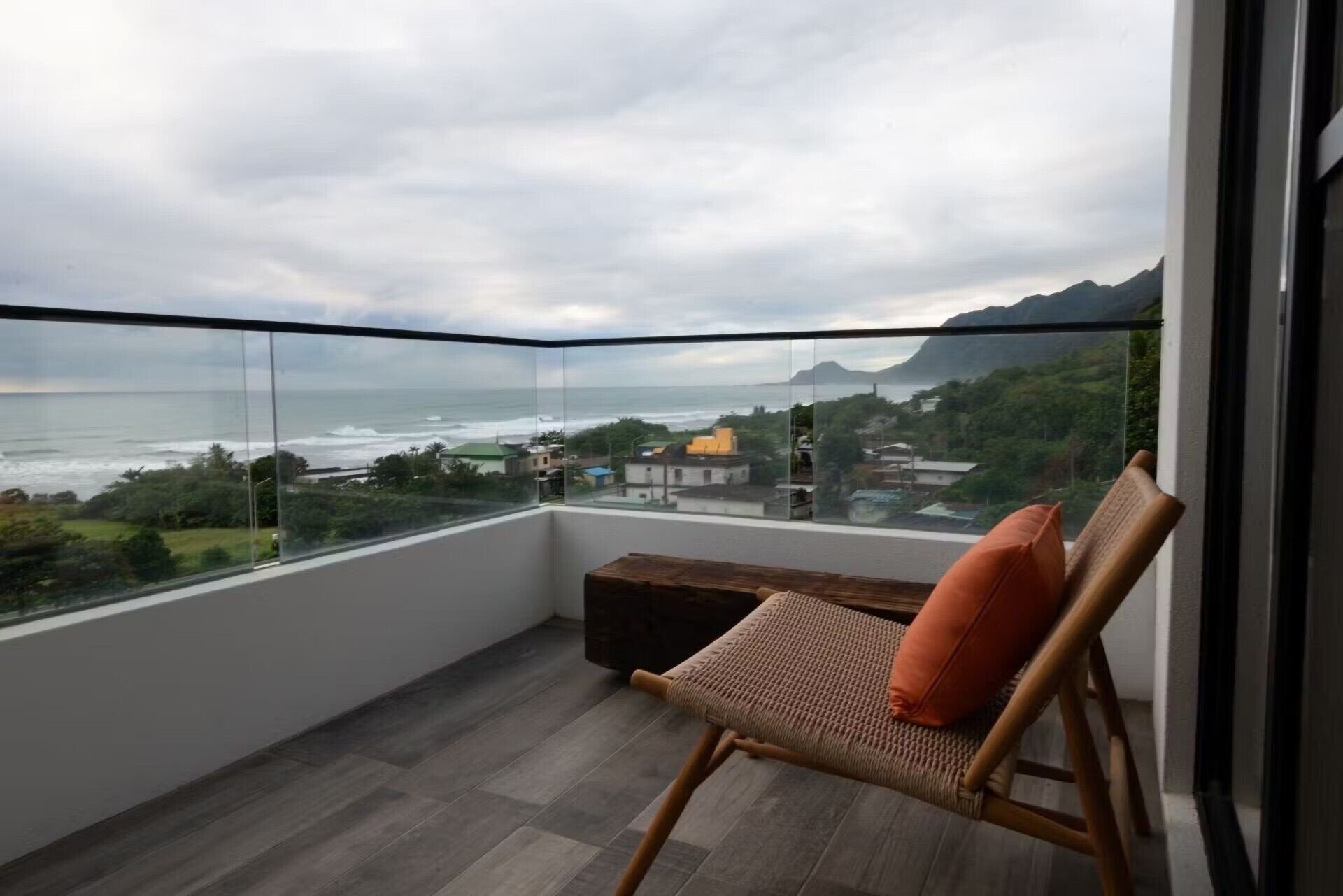 Ein Balkon mit Blick auf den Ozean und ein Sessel mit Kissen.