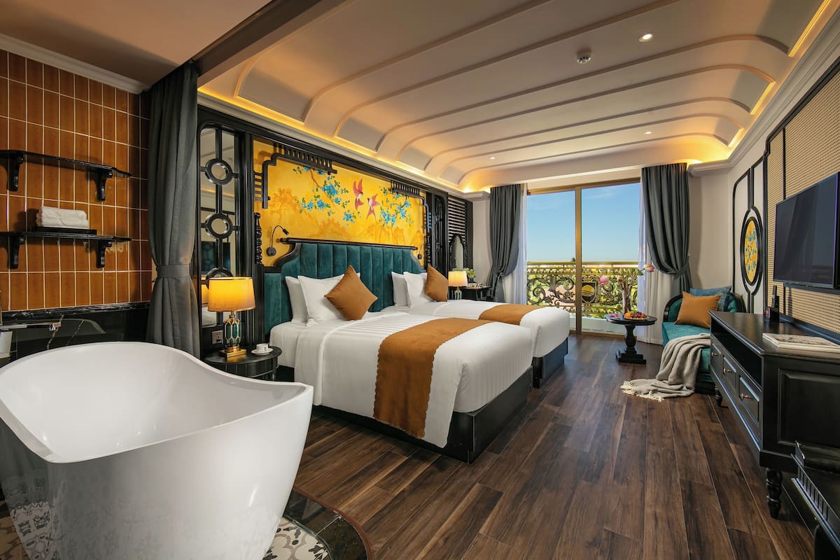Une chambre d’hôtel avec un grand lit, une baignoire, une télévision et un balcon avec vue.
