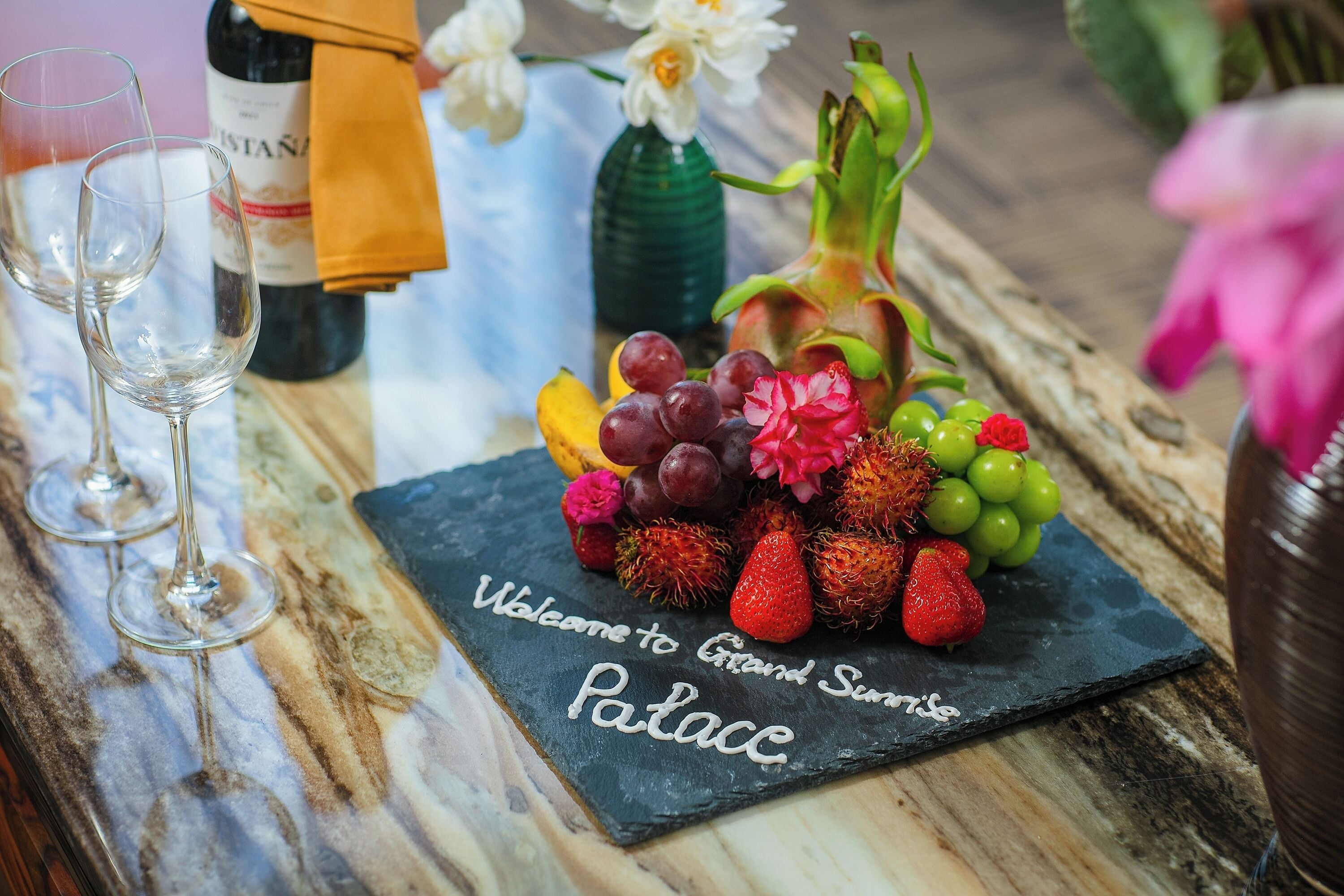 A welcome sign at a restaurant with a fruit and wine display.