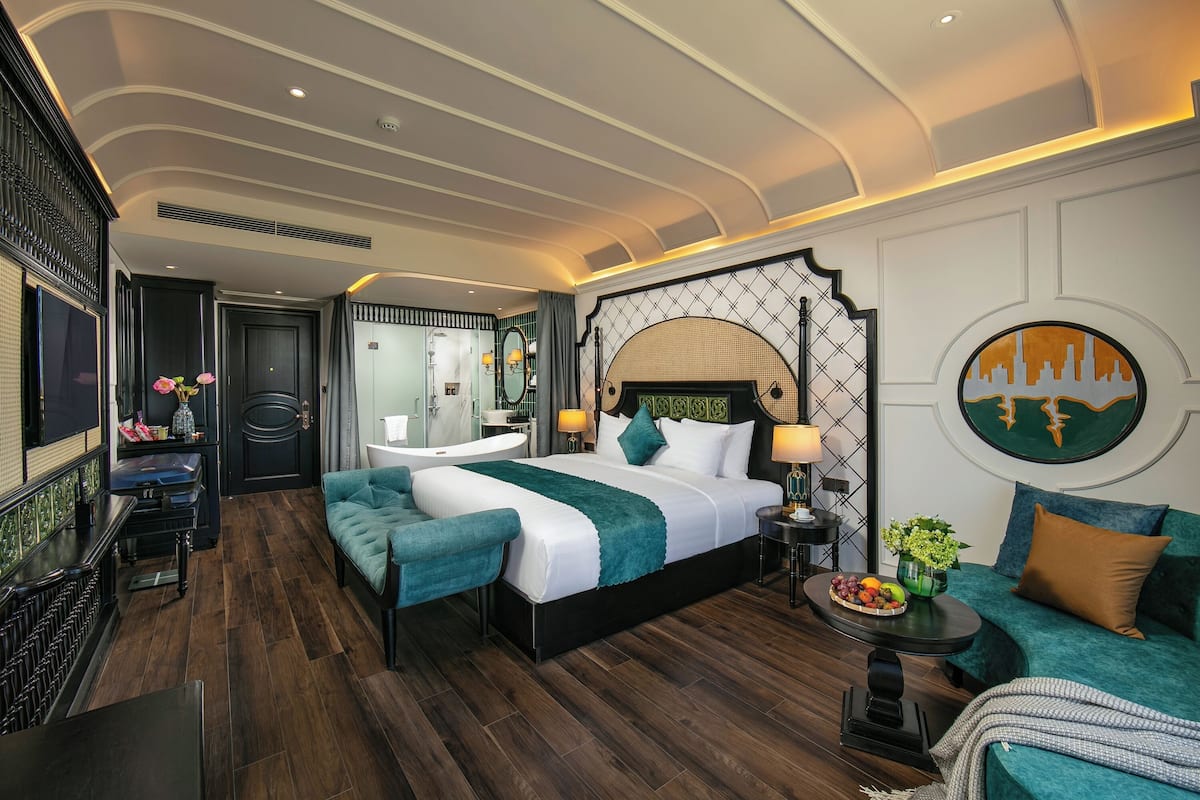 Une chambre d’hôtel moderne dotée d’un grand lit, d’un coin salon, d’une coiffeuse et d’une table à manger.