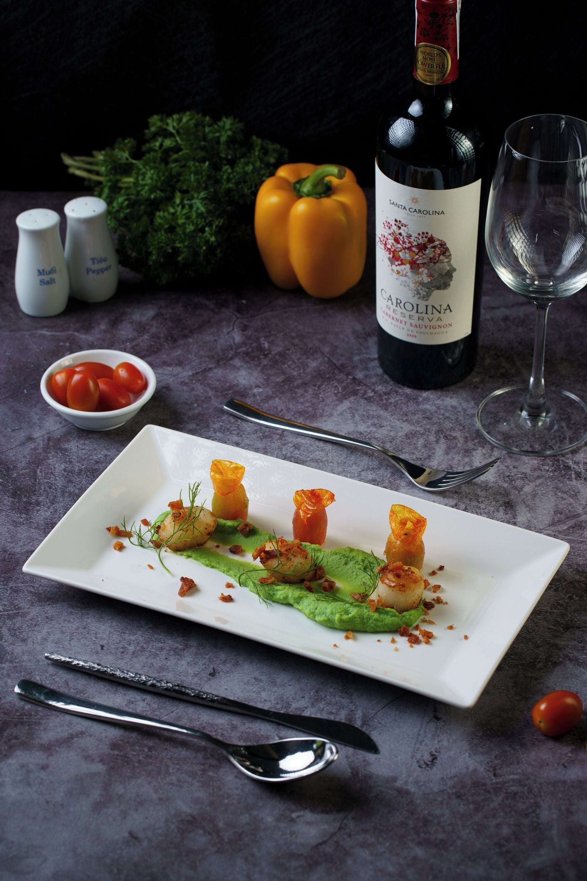 A plate of food with a bottle of wine and a glass on a table.