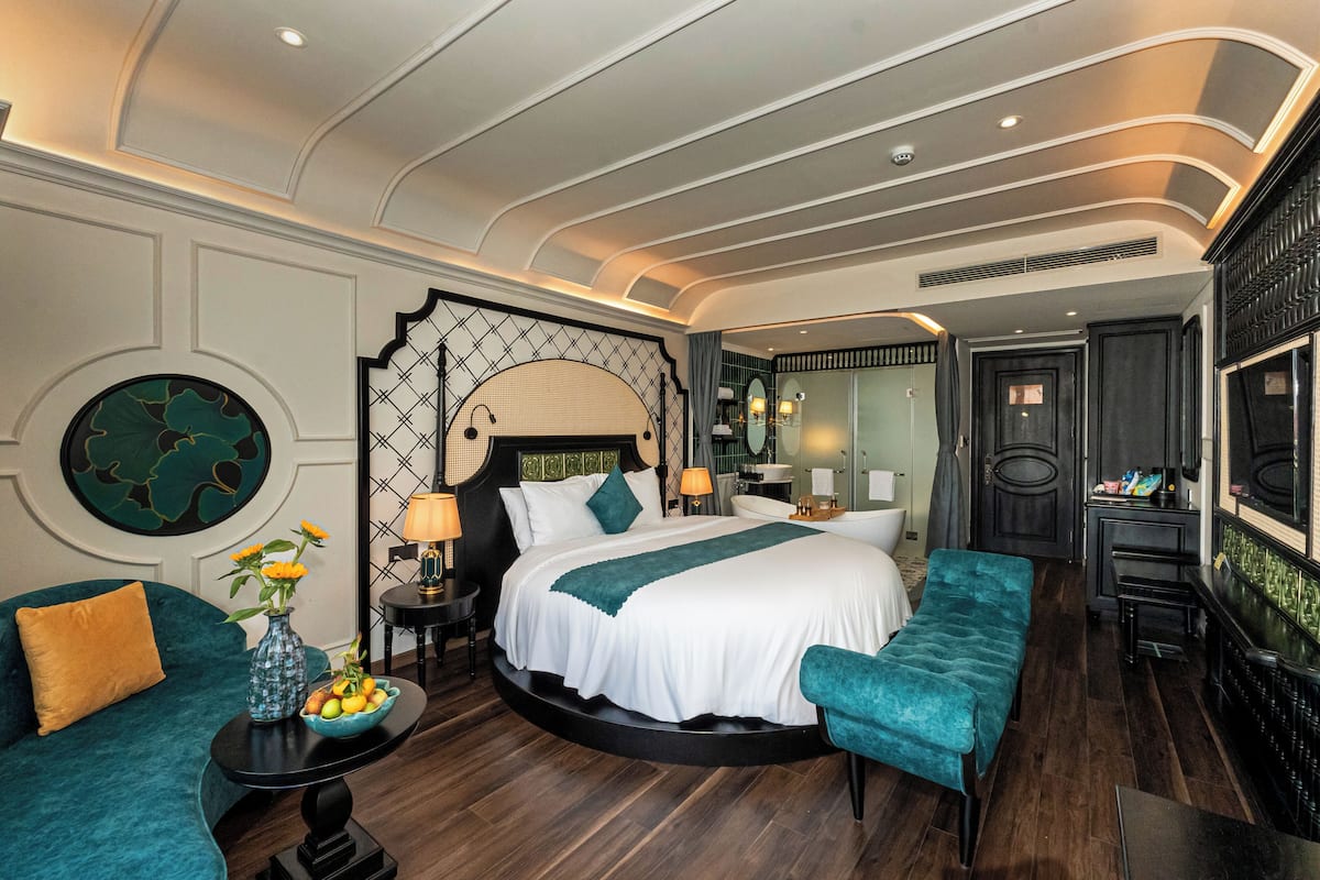 Une chambre à coucher luxueuse avec un grand lit, un coin salon circulaire et un bar.