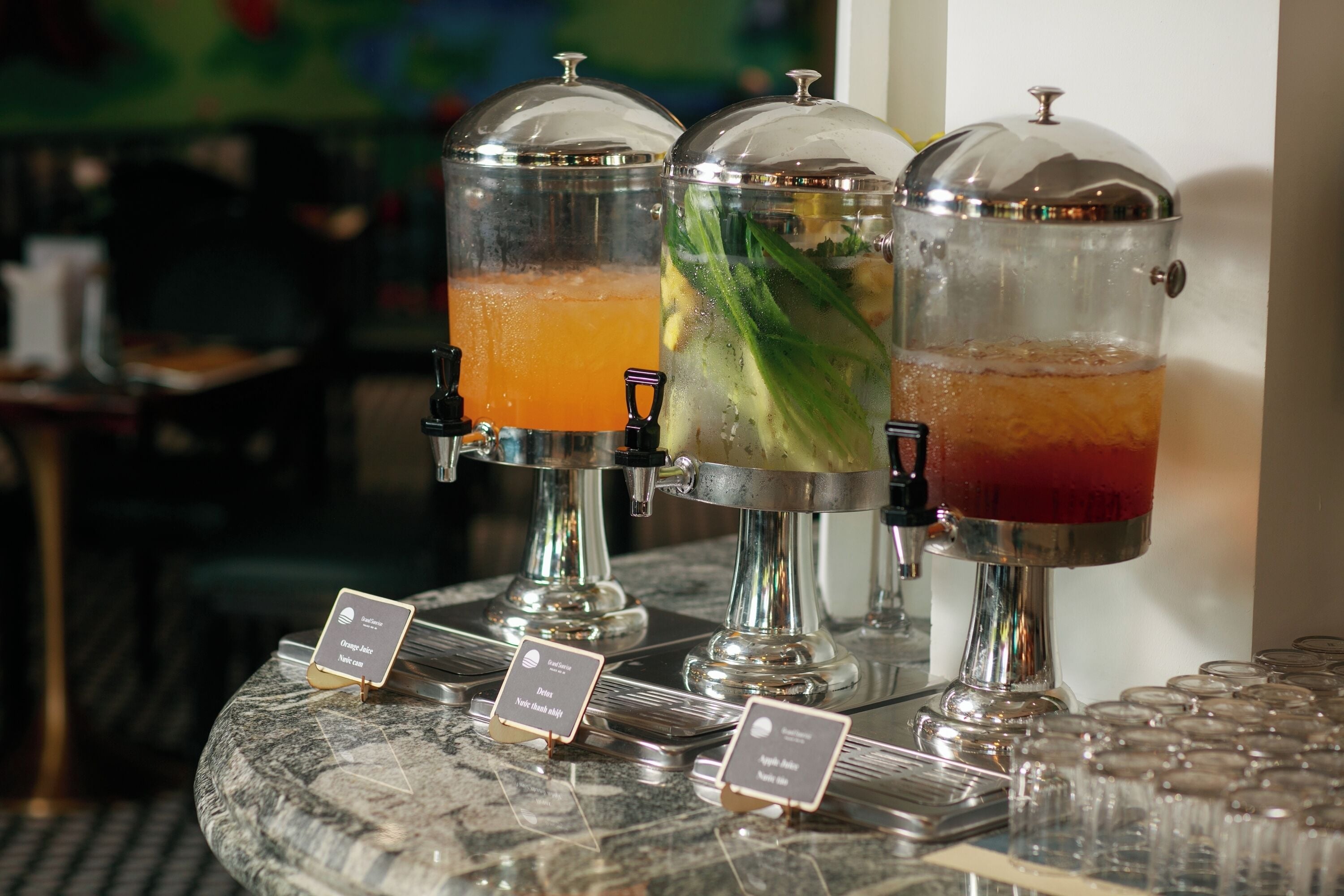 Tres dispensadores de bebidas con etiquetas sobre una encimera de mármol.