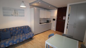 A compact living space with a sofa, a dining table, and a kitchenette. - Alideco - Lignano Sabbiadoro (Lignano Sabbiadoro)